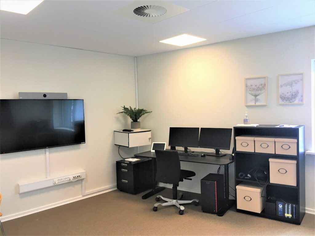 Billede af en del af terapilokalet hvor eksponeringen foregår, her vises computer, skærme og skrivebord